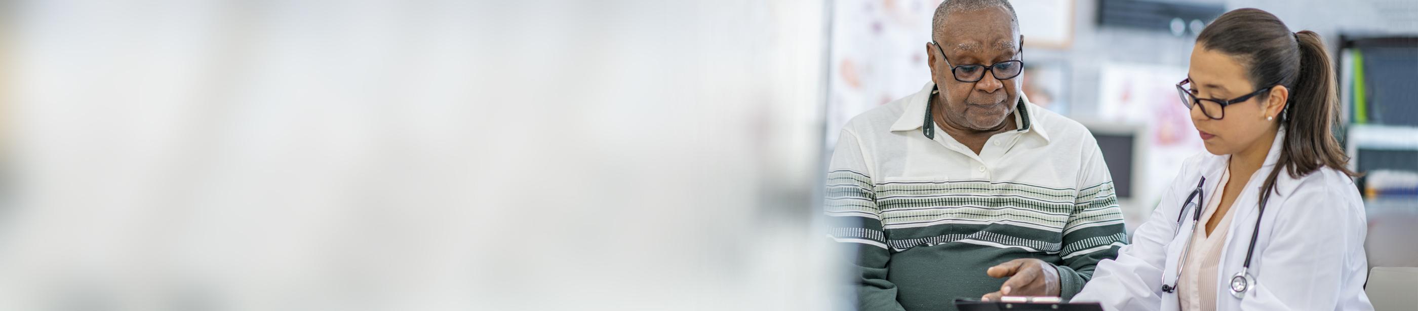 Doctor showing senior patient a tablet